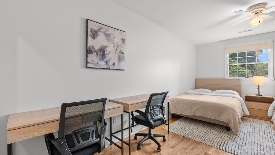 Upper-level bedroom with two full beds, two writing desks, and generous closet space.v