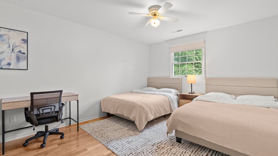 Upper-level bedroom with two full beds, two writing desks, and generous closet space.