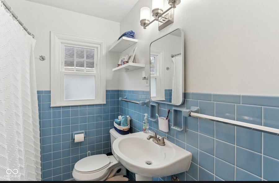 There is a full tub and storage behind the mirror. There is a small shelf unit in the bath. The linen closet is next to the bathroom.