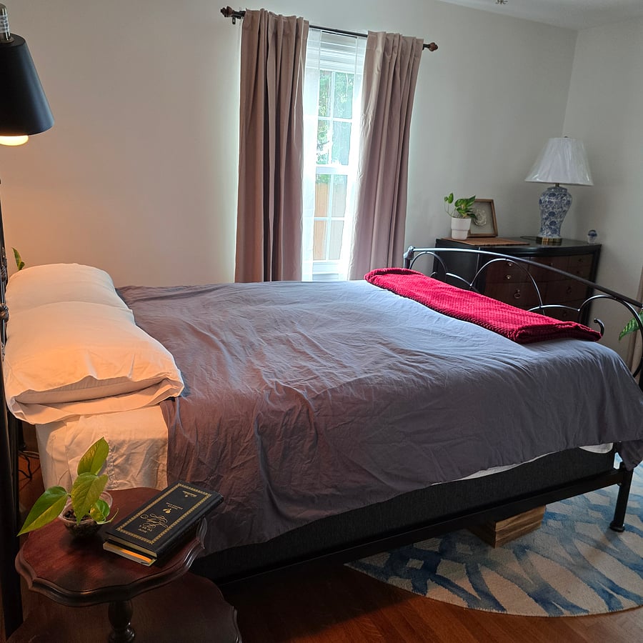 One of two windows with sheer curtains to let the light in and blackout curtains to keep the light out .
