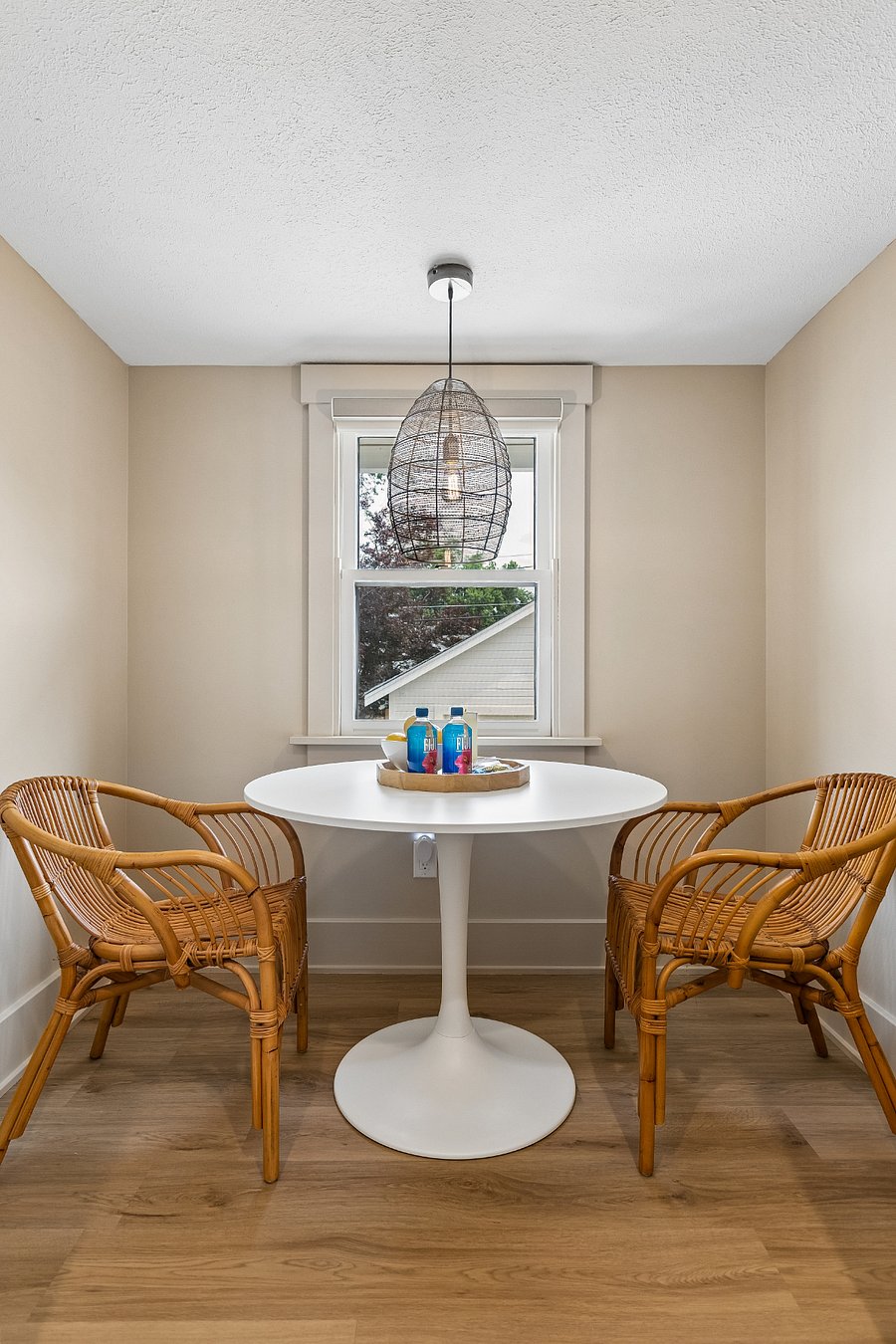 A bright breakfast nook with woven rattan chairs creates an inviting spot to sip coffee, enjoy a meal, or catch up on work.