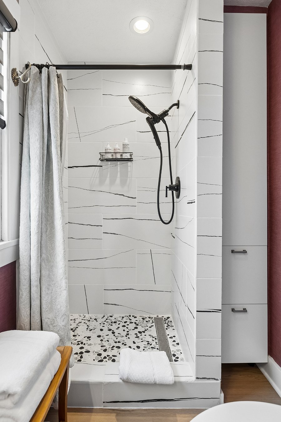 The walk-in shower features an adjustable handheld showerhead with multiple spray settings, starter kit of premium bath products, and plush towels.