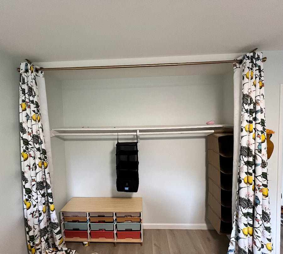 Large closet with small dresser, shoe storage, and hangers