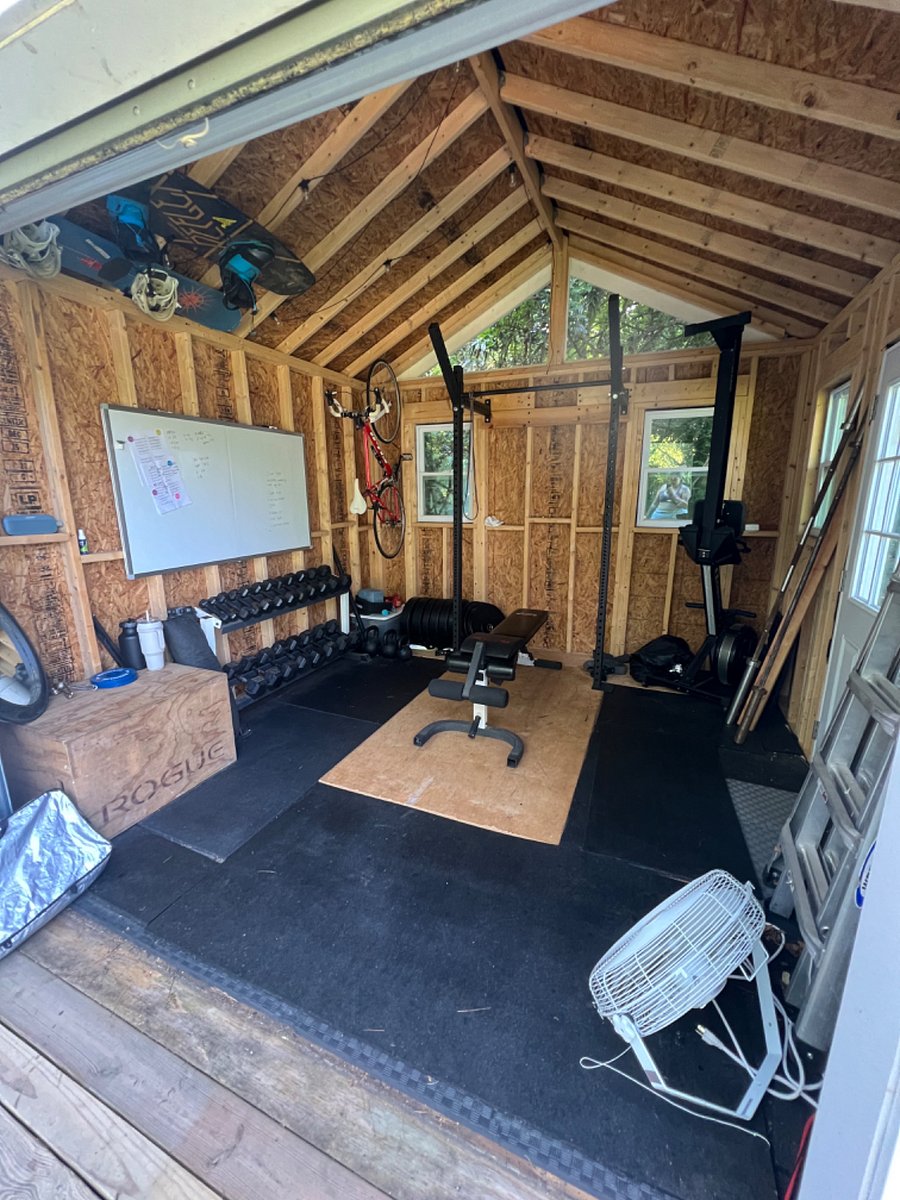 the gym - squat rack, dumbbells, Concept 2 rowing machine, kettlebells, whiteboard, fan
