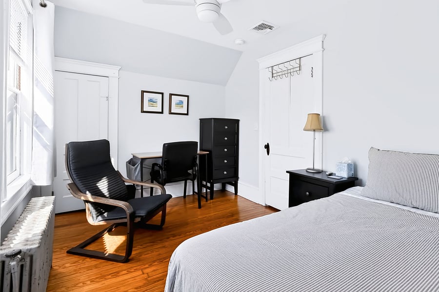 Front bedroom has TWIN bed, ceiling fan, bedside table, dresser, Ikea Poang easy chair, desk and desk chair.