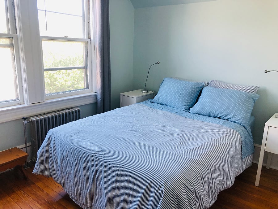 Back bedroom has full size bed, ceiling fan, 2 bedside tables, black out curtains, Ikea Poang easy chair and vintage dresser.