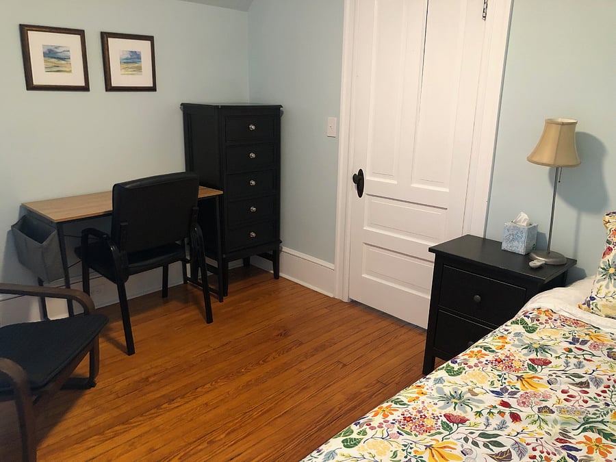 Front bedroom has twin bed, ceiling fan, bedside table, dresser, Ikea Poang easy chair, desk and desk chair.