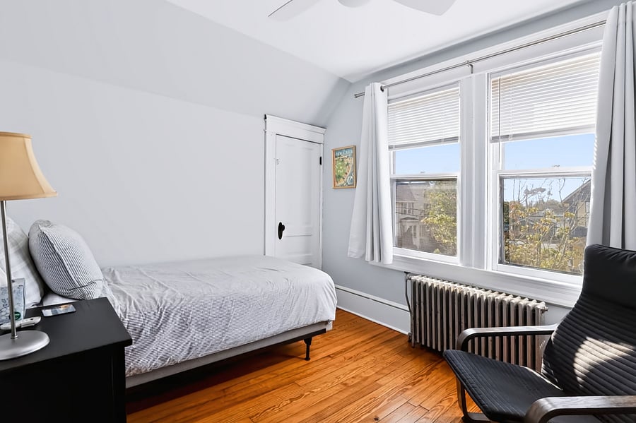 Front bedroom has TWIN bed, ceiling fan, bedside table, dresser, Ikea Poang easy chair, desk and desk chair.