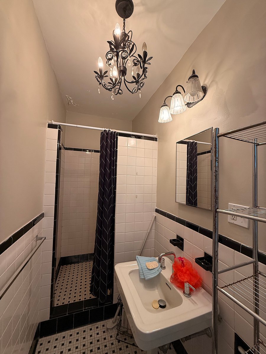 Huge walk-in shower with classic pedestal sink and a huge window. 