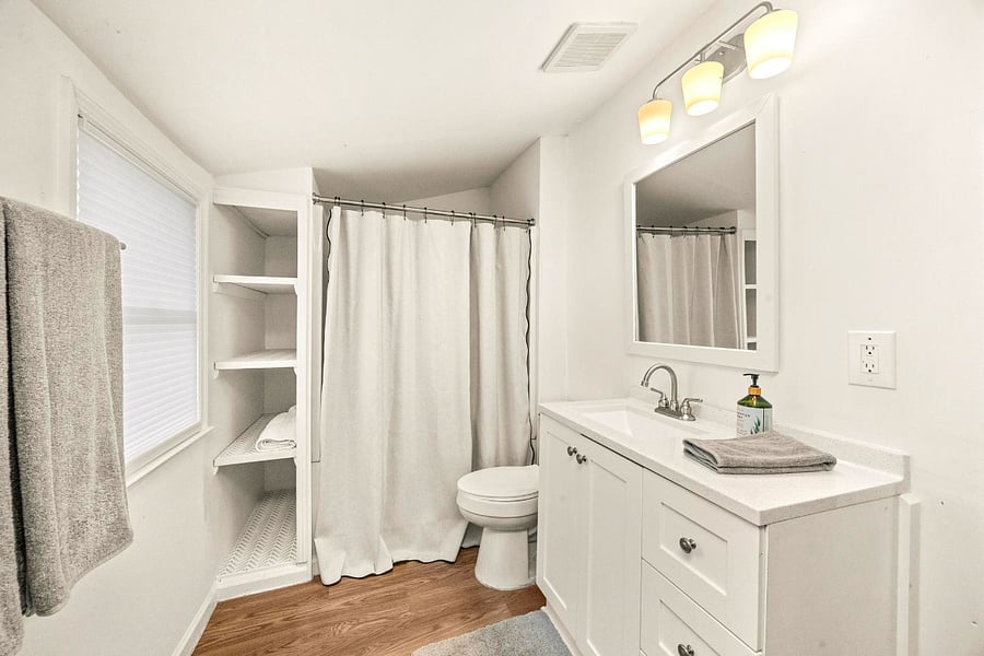 Clean and functional with a full vanity, mirror, and open shelving, everything you need within easy reach!