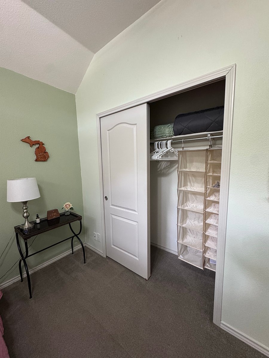 Second bedroom includes: queen sized bed, nightstand, lamp, alarm clock, phone stand, mounted tv, and hanging organizers in the closet.