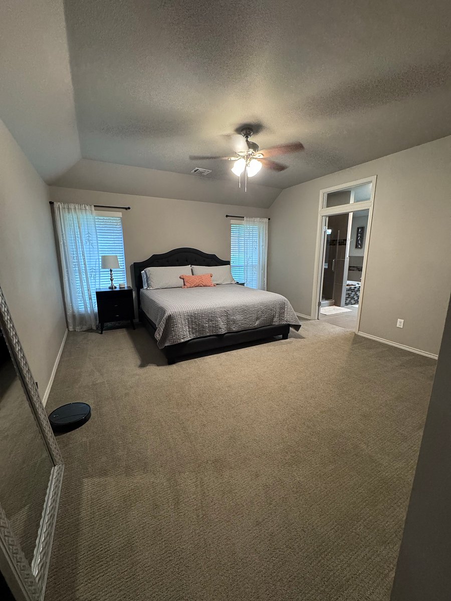 Master bedroom includes: king sized bed, nightstands, full length mirror, small chair, and mounted TV