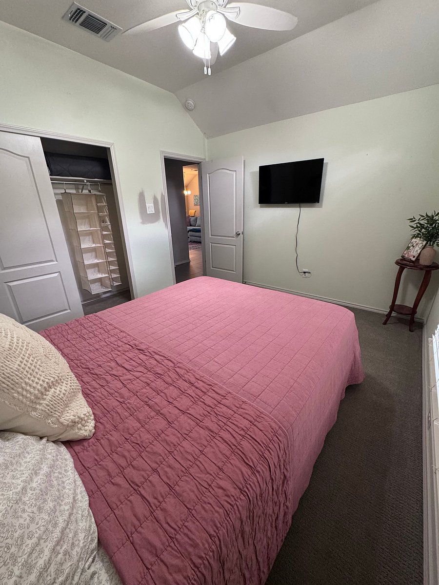 Second bedroom includes: queen sized bed, nightstand, lamp, alarm clock, phone stand, mounted tv, and hanging organizers in the closet.