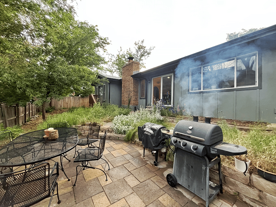 Fully fenced backyard with patio, grill, and deck furniture.