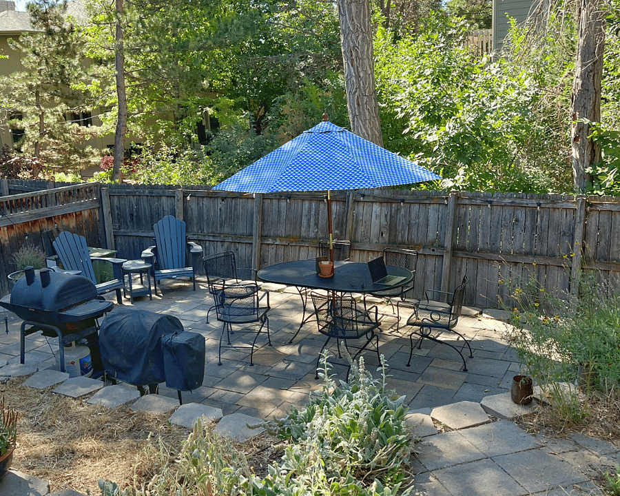 Fully fenced backyard with patio, grill, and deck furniture.