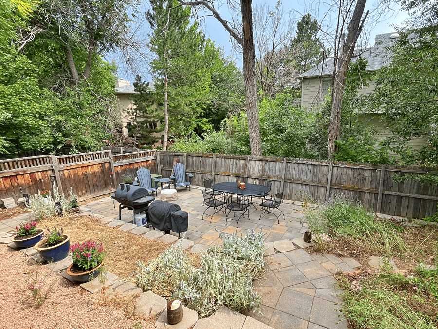 Fully fenced backyard with patio, grill, and deck furniture.