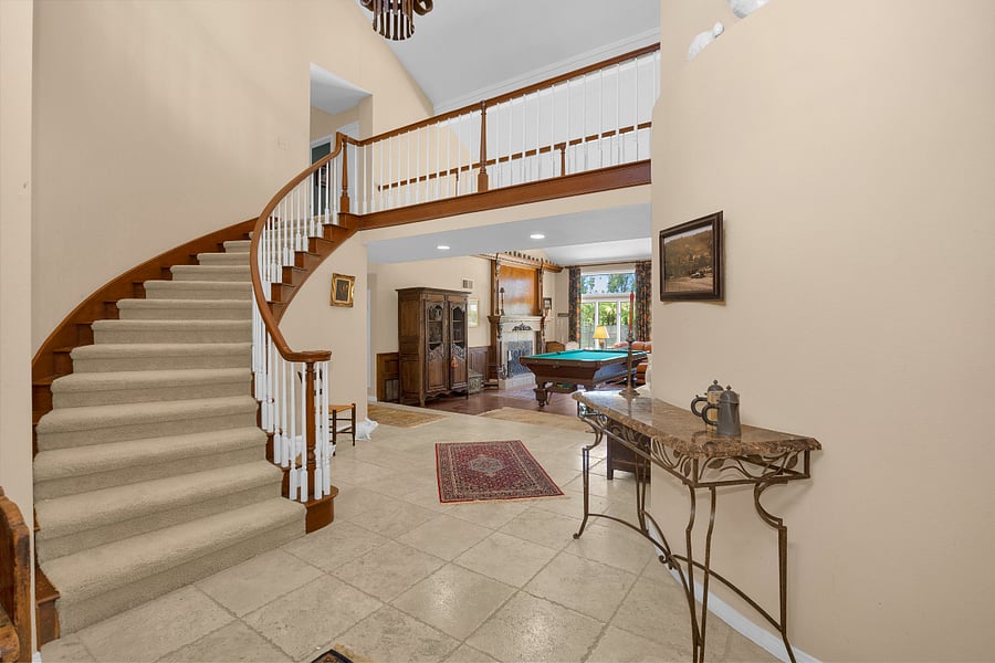 Spacious two-story entry with a sweeping staircase and an open view into the homes main living and entertainment areas.