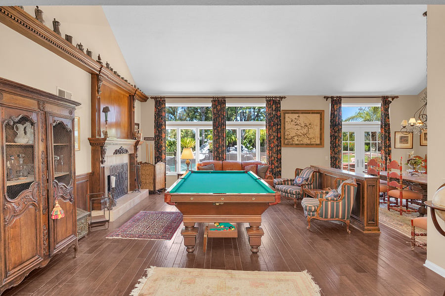 Spacious entertainment area featuring a pool table, cozy fireplace, comfortable seating, and abundant natural light.