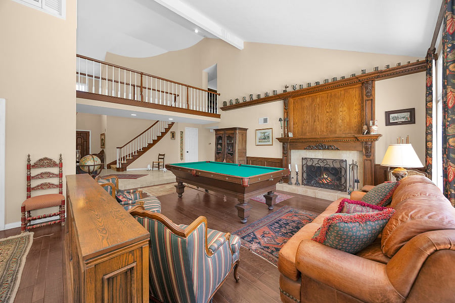 Warm and spacious entertainment area featuring a full-size pool table, impressive fireplace, and comfortable seating for relaxing and gathering.