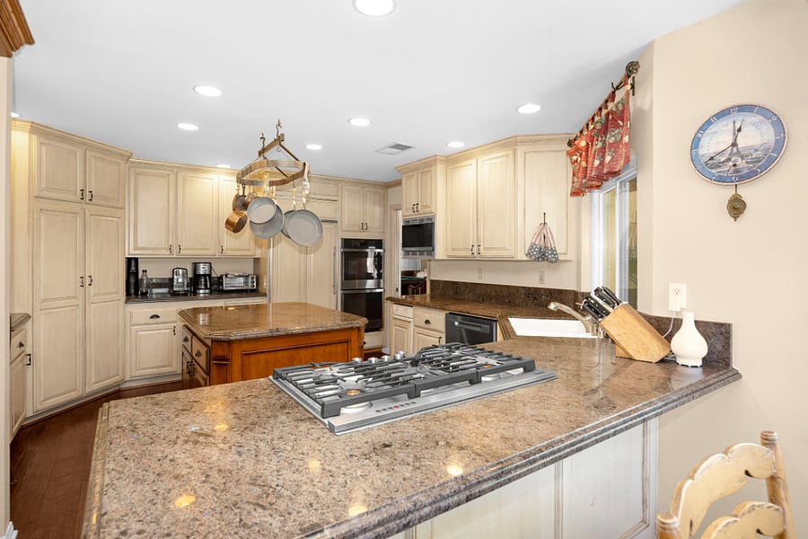 Spacious, fully equipped kitchen with granite counters, gas cooktop, double ovens, center island, and ample storage for comfortable long-term living.