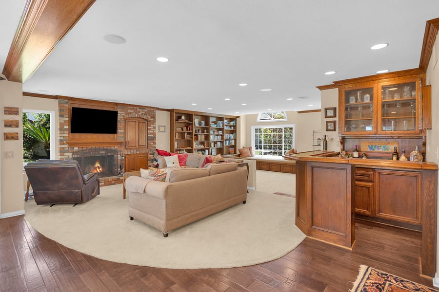 Comfortable family room with fireplace, large TV, built-in bookshelves, wet bar, and plenty of space to relax and unwind.