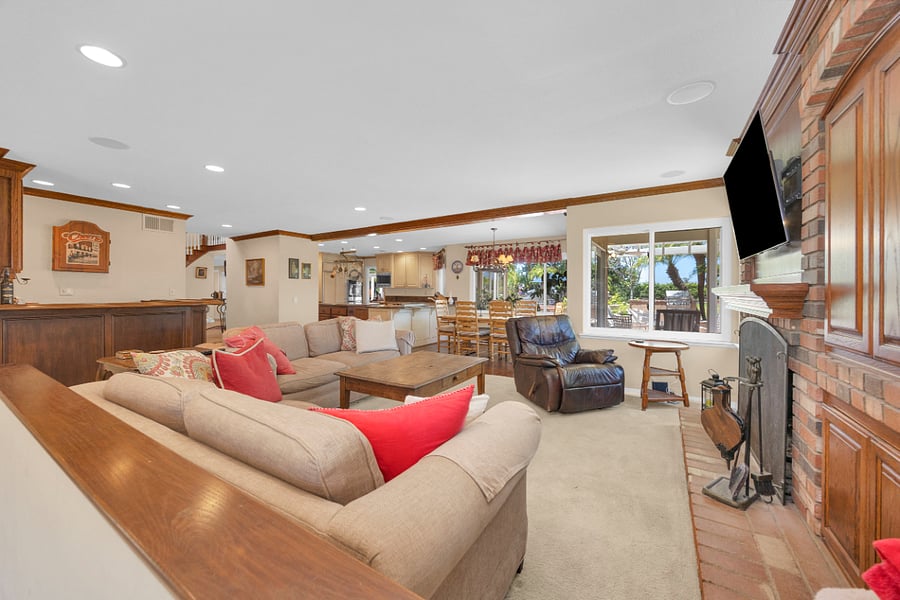 Spacious family room with comfortable seating, fireplace, large TV, and an open layout connecting seamlessly to the kitchen and backyard.