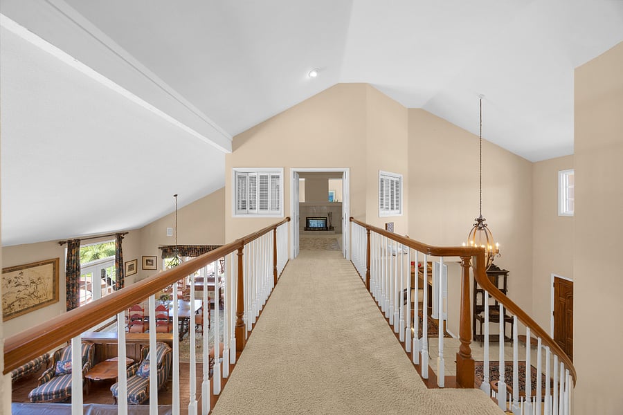 Open upper-level walkway overlooking the main living areas, highlighting the homes spacious two-story layout and open design.