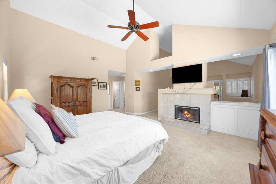 Spacious primary suite with vaulted ceilings, king bed, fireplace, and TV, creating a comfortable private retreat within the home.