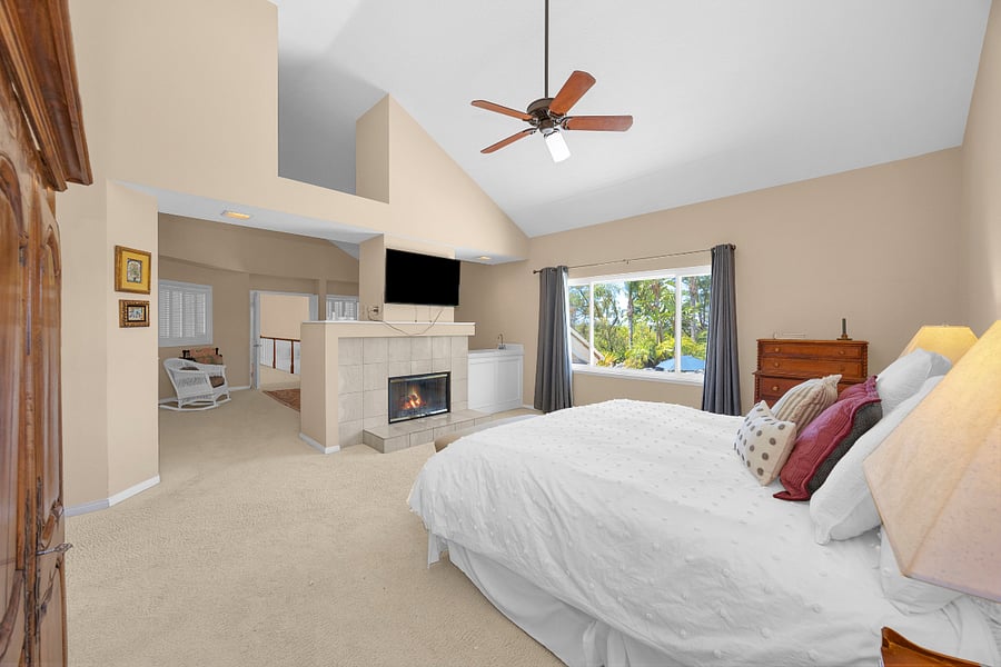 Expansive primary suite with king bed, vaulted ceilings, fireplace, TV, and abundant natural light for a comfortable private retreat.
