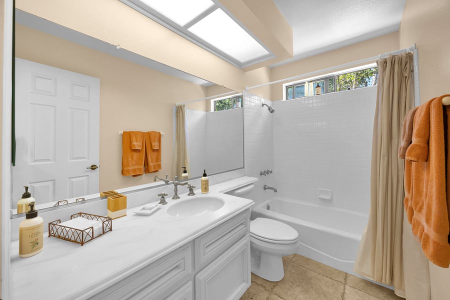 Bright shared full bathroom with a spacious vanity, tub and shower combination, and plenty of natural light.