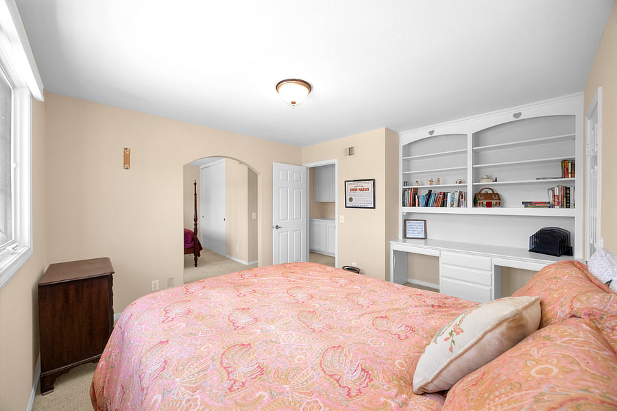 Comfortable queen bedroom with built-in shelving and workspace, offering plenty of storage and a convenient place to work or study.