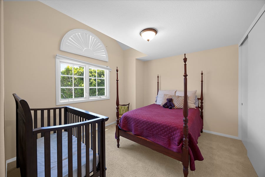 Comfortable full bedroom with plenty of natural light and a crib, offering a welcoming setup for families traveling with little ones.