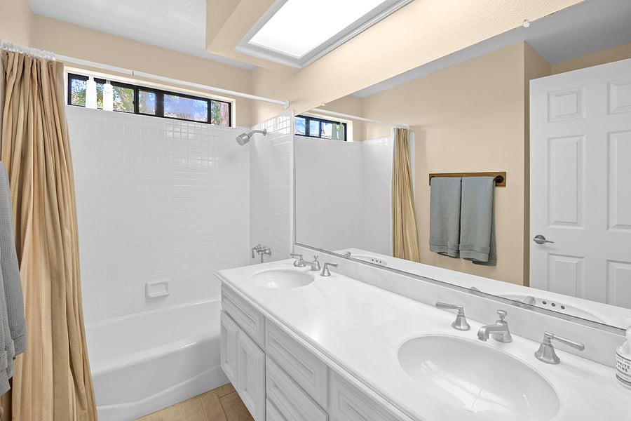 Bright shared bathroom with dual sinks, a tub/shower combination, and plenty of counter space, making it easy for multiple guests to get ready.