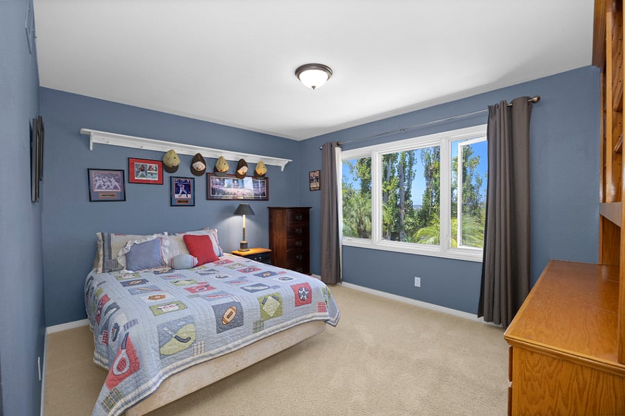 Comfortable, light-filled bedroom with a queen bed, private ensuite bath, & plenty of space to settle in, and large windows overlooking the surrounding greenery.