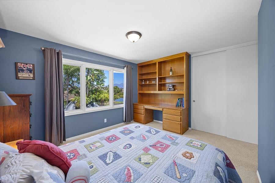 Bright queen bedroom with beautiful garden and hillside views, plus built-in shelving and a workspace for added convenience.