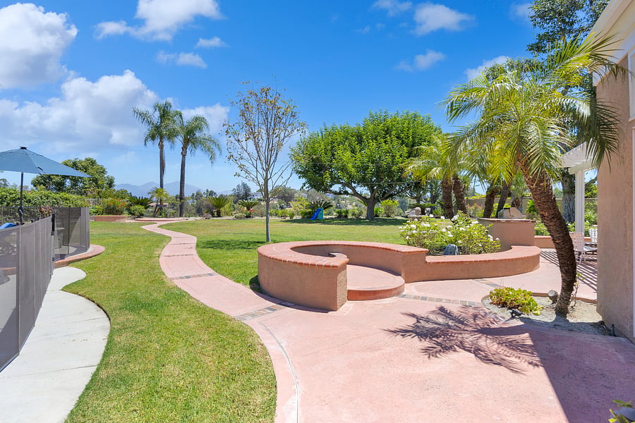 Gather around the outdoor fire pit for relaxed evenings under the California sky, surrounded by lush lawns, tropical landscaping, and beautiful hillside views.