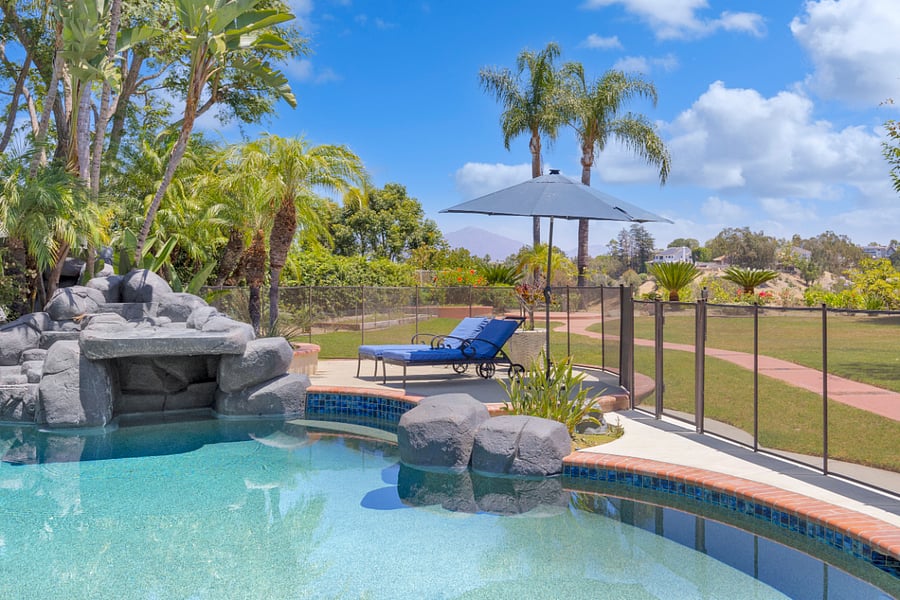 Relax poolside under the umbrella while enjoying the rock waterfall, tropical landscaping, and beautiful hillside views surrounding the backyard.