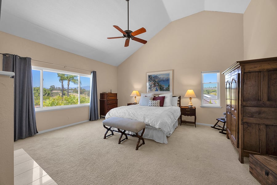 Luxurious primary suite featuring a California King bed, vaulted ceilings, and peaceful neighborhood views.