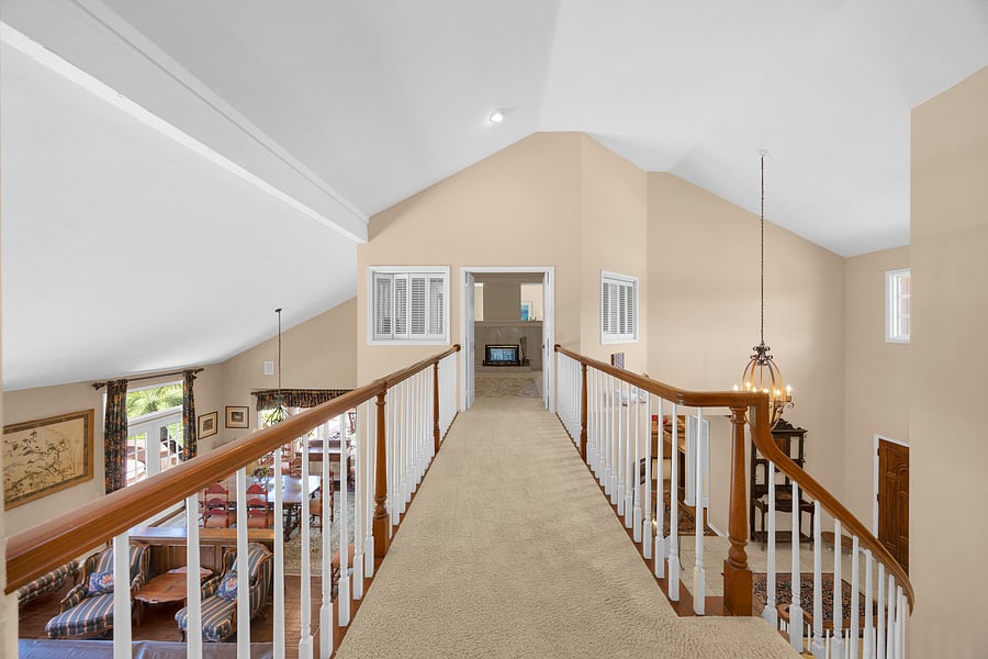 Open upper-level gallery leads to the private primary suite while overlooking the home's grand foyer and living spaces.