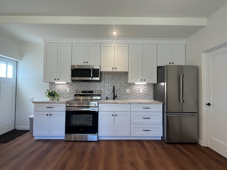 Kitchen features brand new construction bright white wood cabinetry, bronze hardware, Taj Mahal Quartzite countertops, Samsung Stainless Oven & Microwave, full sized refrigerator, lots of storage, fully stocked.