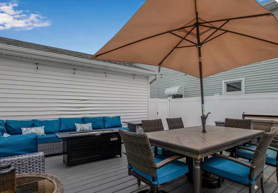 Backyard deck with table, sectional, gas grill and fire table. 