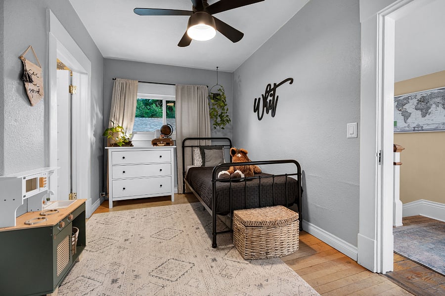 Small bedroom with twin bed, dresser, lamp and small closet with shelving storage and laundry shoot.