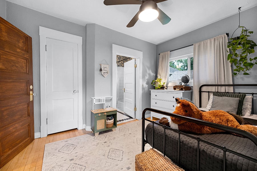 Small bedroom with twin bed, dresser, lamp and small closet with shelving storage and laundry shoot.