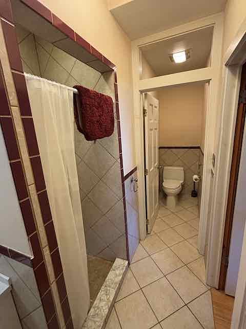 Bath has separate toilet niche and tiled shower.