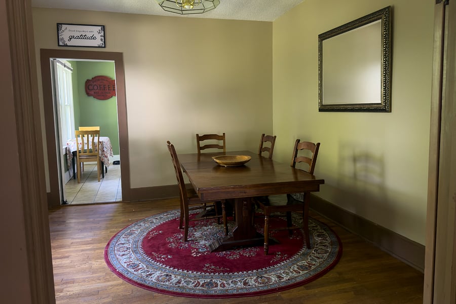 A proper separate dining room solid wood trestle table, Persian rug, and seating for eight. The kind of room that makes a takeout pizza feel like a dinner party.