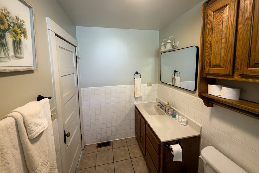 Original wood cabinetry, black hardware, and subway tile halfway up the walls the kind of bathroom that got better with age.