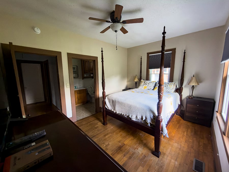 The master from the other side en suite bath through the left door, original hardwood floors throughout, and a four-poster that makes every other bed feel like a compromise.