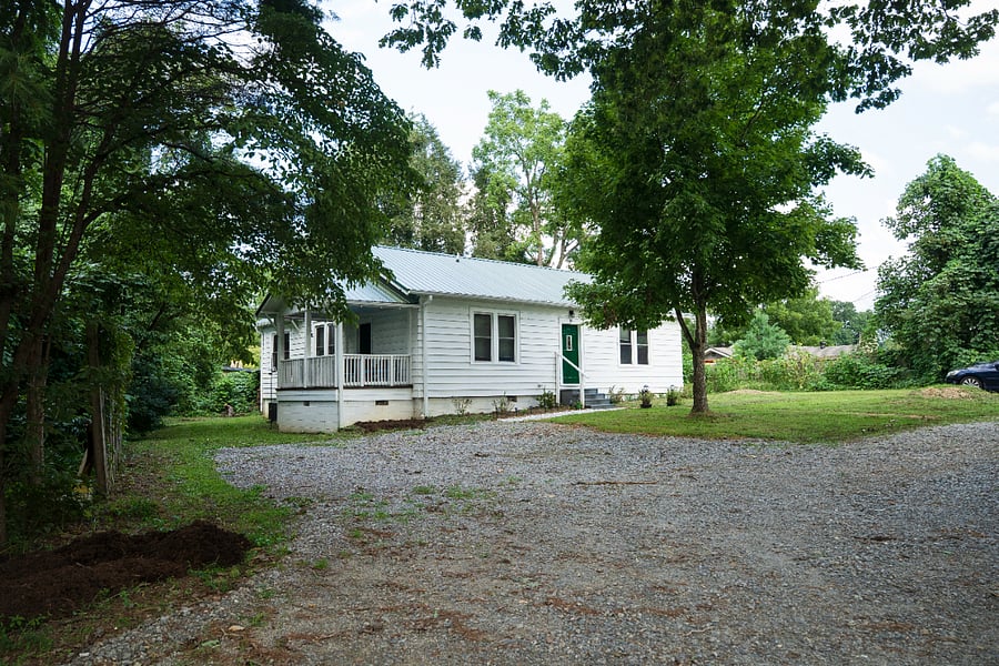 The full parking area private gravel lot with room for three vehicles, tucked under mature trees just steps from the front porch.