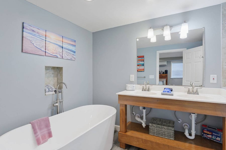 Bathroom with over size tub for soaking, 2 sinks, and a walk in tiled shower, and toilet.