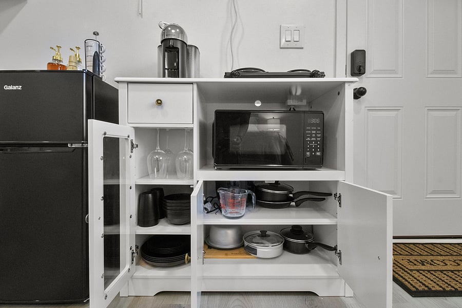 Mini fridge, microwave, coffee maker, and electric cooktop for simple meal preparation.Includes cookware, dishes, utensils, glassware, rice cooker, and everyday kitchen essentials.